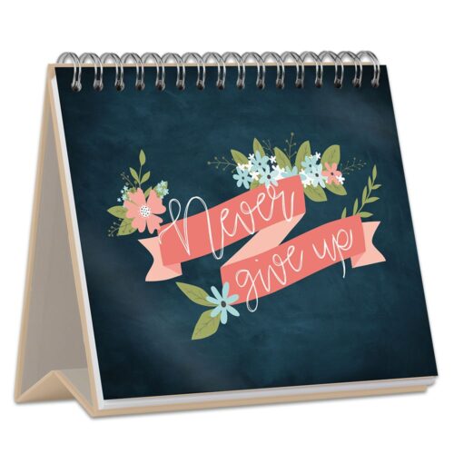 Ein spiralförmiger Tischkalender mit floralen Motiven und dem motivierenden Text „Gib niemals auf“ in Schreibschrift.