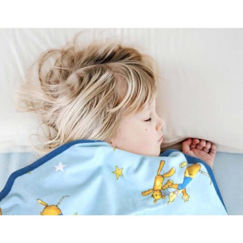 Kleines Kind schläft unter einer bunten Decke und ruht friedlich auf einem Kissen.