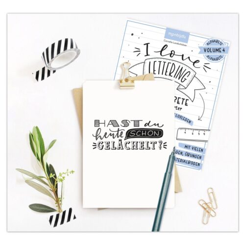 Ein Klemmbrett mit einem Zettel mit der Aufschrift „Hast du heute schon gelächelt?“ umgeben von Briefpapier und Blättern.