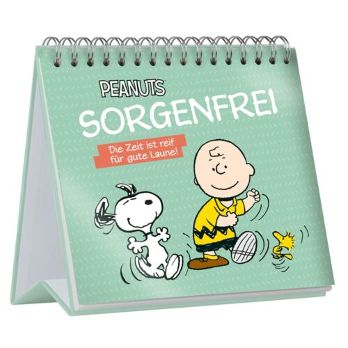 Charlie Brown, Snoopy und Woodstock laufen freudig über einen Tischkalender mit dem Titel „Sorgenfrei“ und grünem Einband.